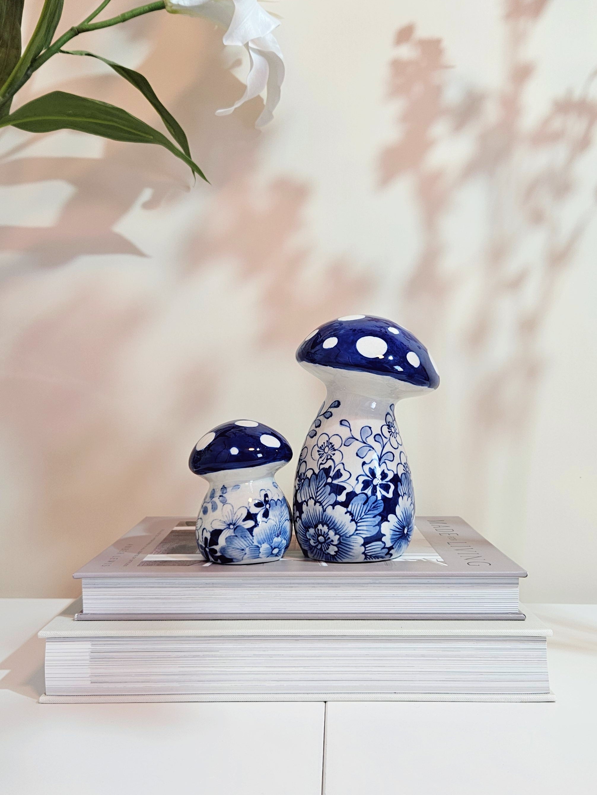 set of 2 blue and white chinoiserie porcelain mushroom figurines placing on a book with beige background
