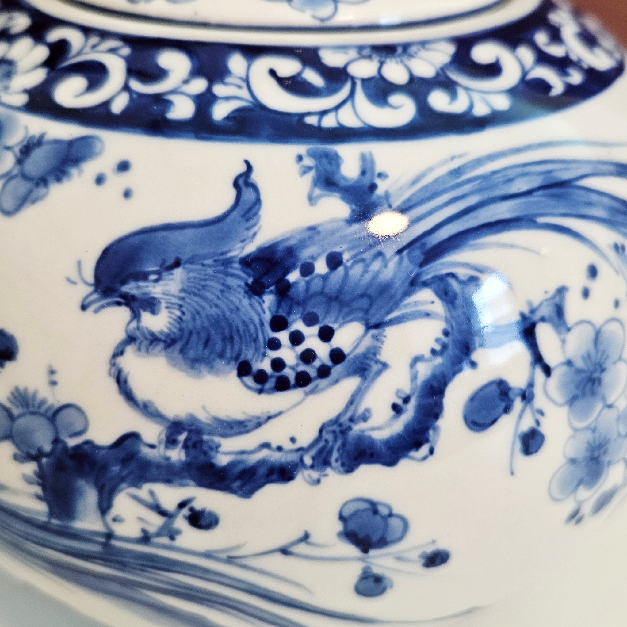 Close-up of a blue and white porcelain ceramic piece featuring a detailed pheasant bird  with floral motifs.
