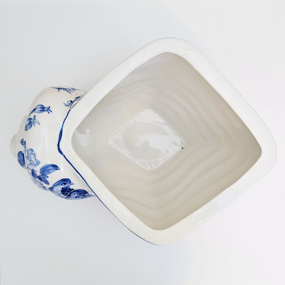 An antique-style ceramic planter pot with a shell shape glazed interior and a side handle decorated in blue floral patterns, shown from an overhead angle on a white background.